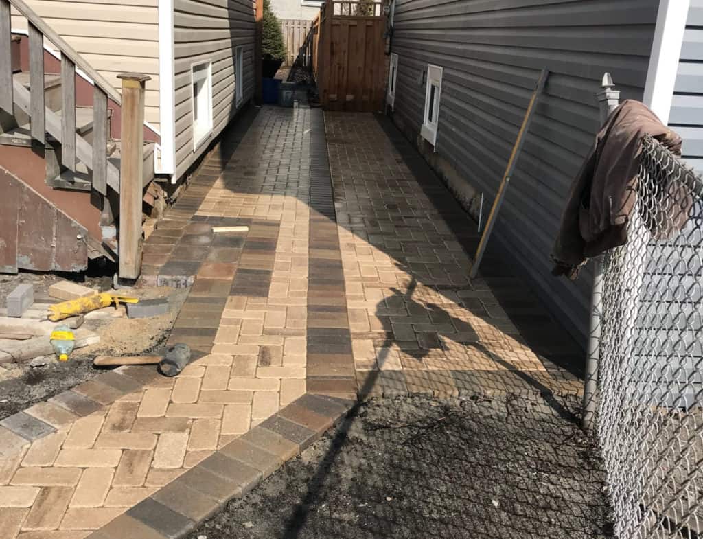Paver walkway installation underway in a Chicago backyard, herringbone pattern and joint lines forming