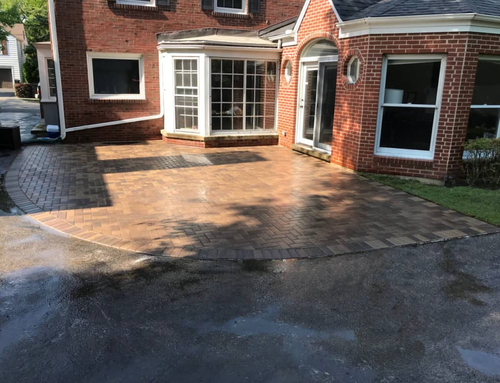Herringbone brick paver patio pitched away from a Chicago-area brick home's foundation