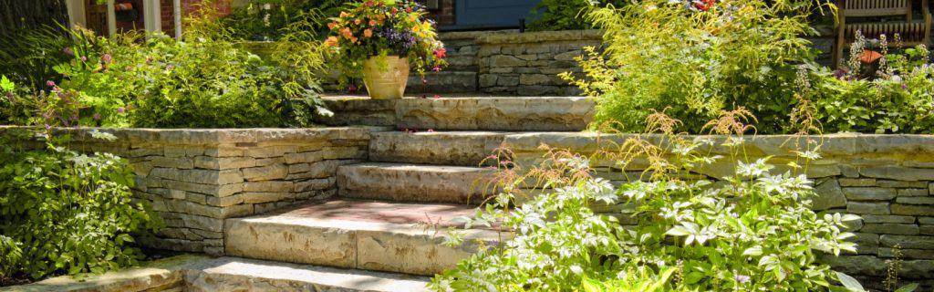 Landscaped front entry with a stone retaining wall, steps and flowering plant beds