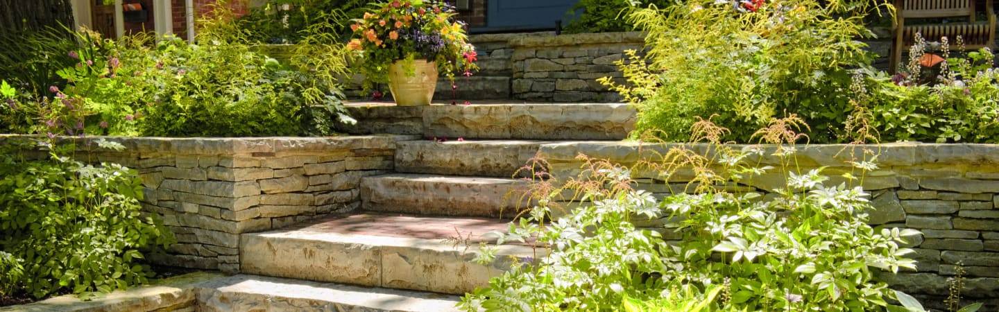 Tiered retaining walls with planted garden beds on a sloped North Shore yard