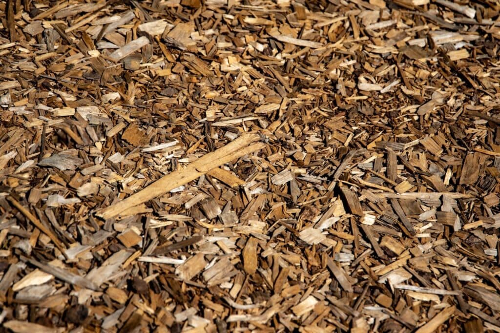 Fresh brown bark mulch chips in sunlight, the bulk material priced and delivered by the yard