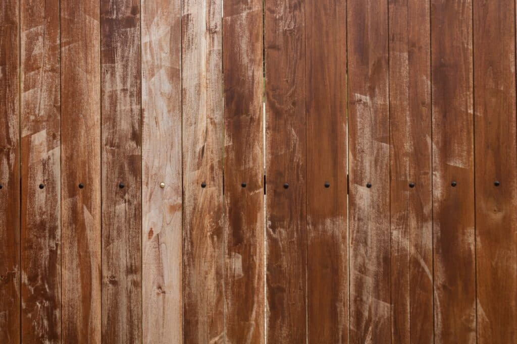 Vertical cedar-toned fence boards with narrow spacing and visible fasteners, showing board style
