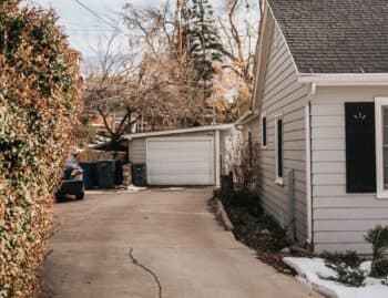 Concrete driveway with a long surface crack running toward a garage in a wintry Chicago yard