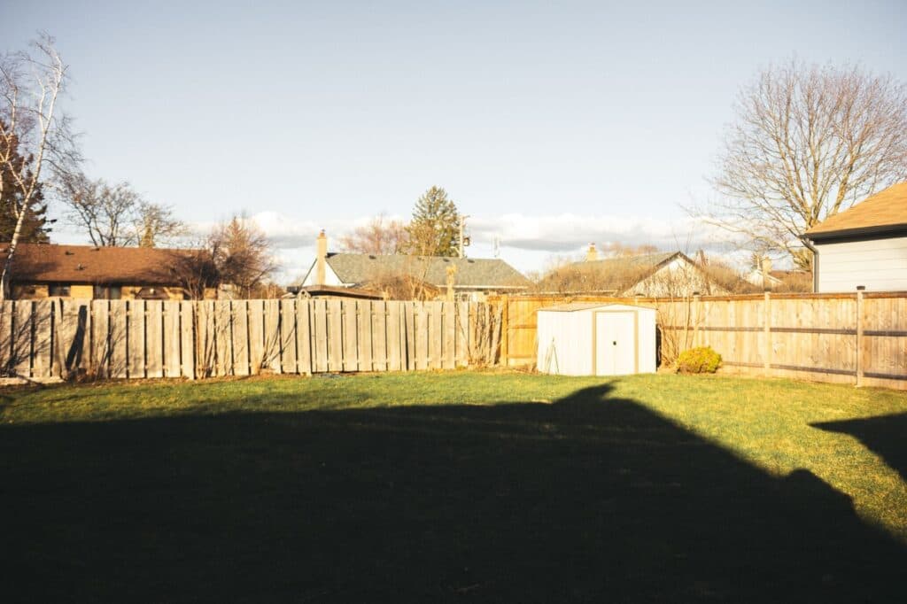 Weathered wood privacy fence enclosing a Chicago-area backyard with a shed and bare winter trees