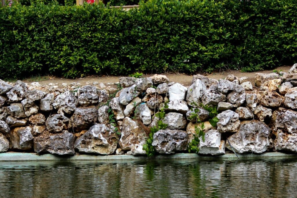Low stacked stone wall holding a raised planted bed with a hedge above it, a Chicago-area retaining wall design