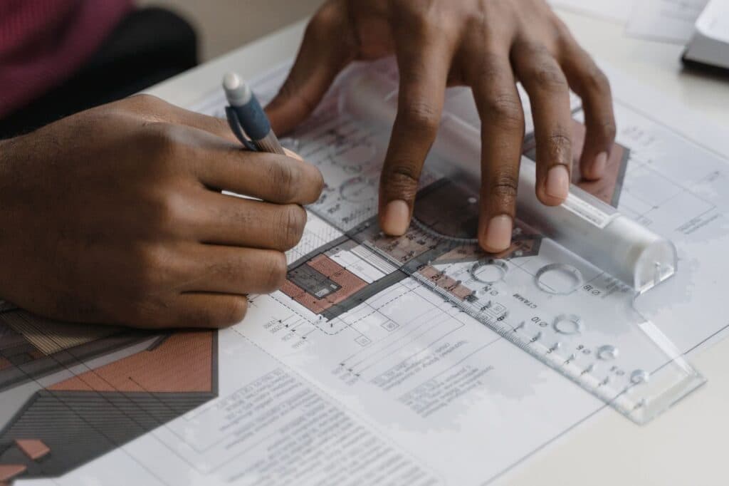 Hands reviewing a landscape design plan with a ruler and pencil during the concept design stage