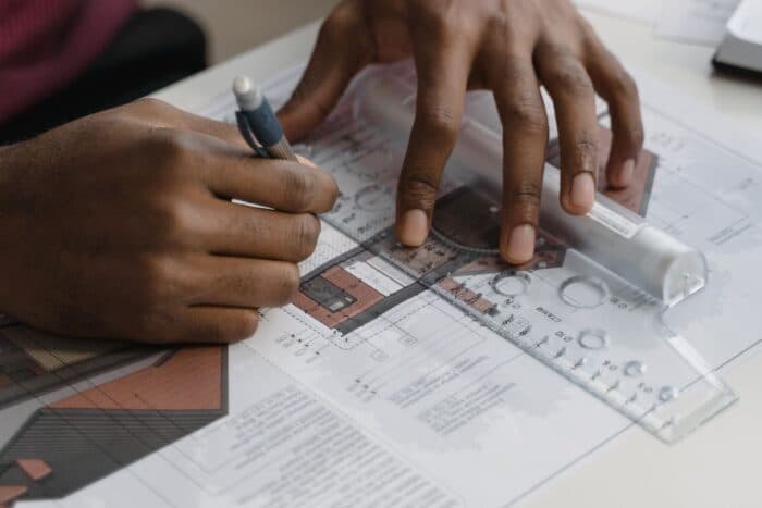Hands reviewing a landscape design plan with a ruler and pencil during the concept design stage