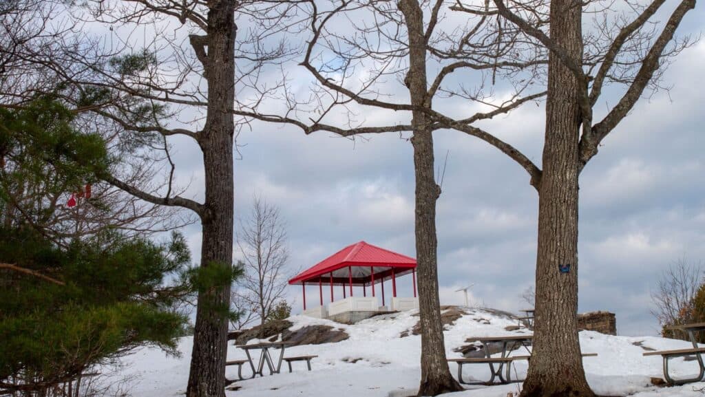 Red-roofed pavilion on a snow-covered hillside, showing how a solid roof carries winter load