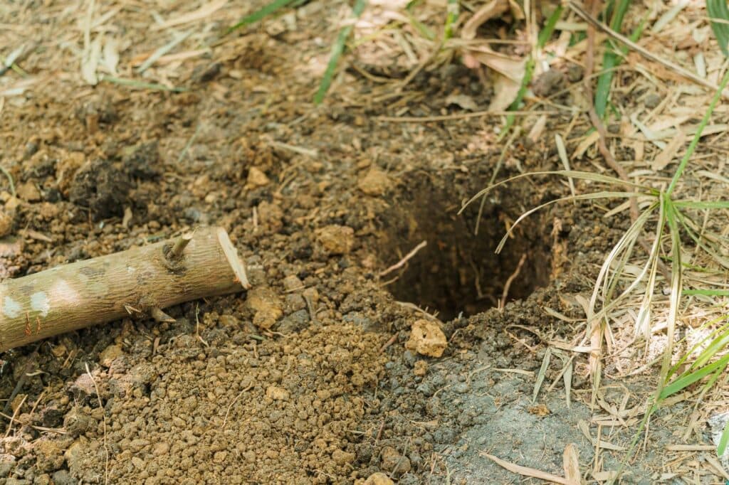 Freshly dug hole in the yard, the first step in setting a pergola post footing below frost depth