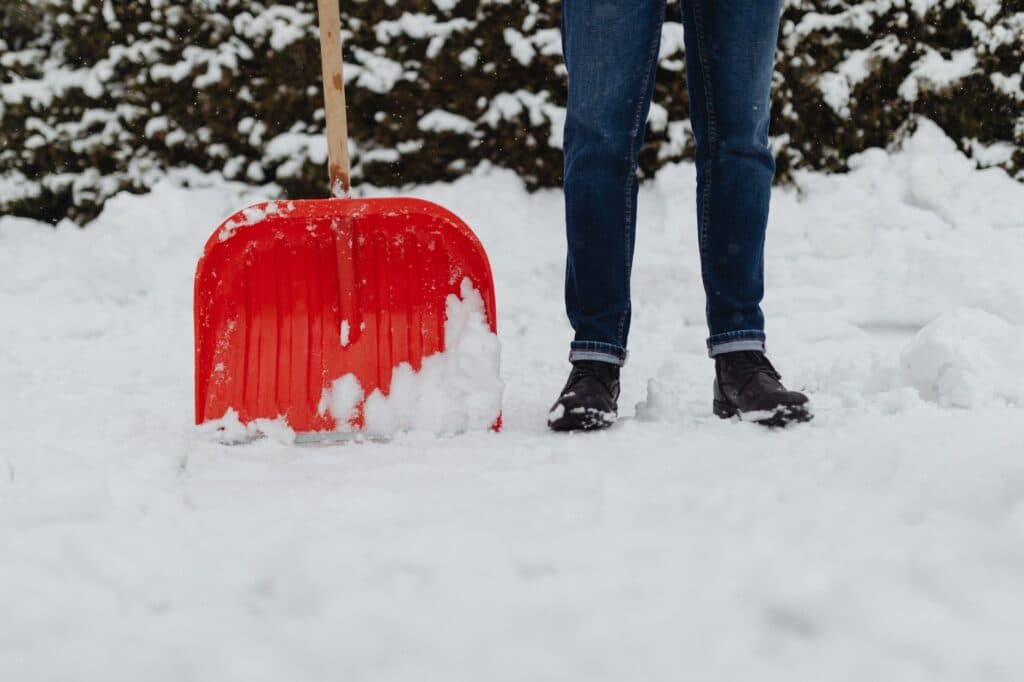 Homeowner clearing snow with a plastic shovel at a Chicago-area home, safe for artificial turf systems