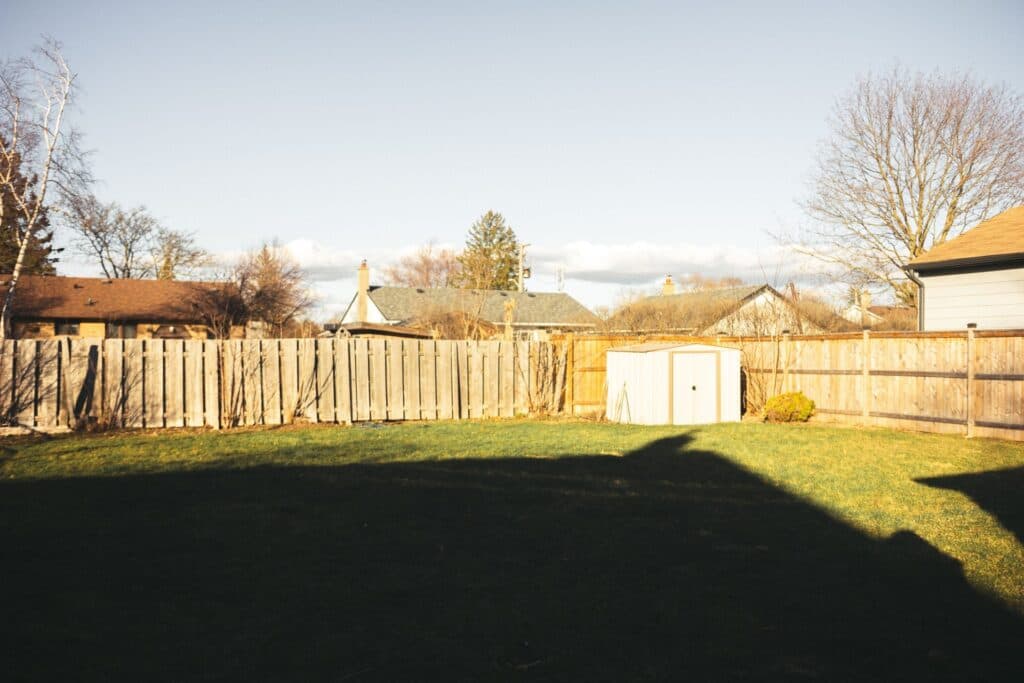 Residential backyard lawn bordered by a wooden fence and shed, the kind of Chicago-area yard a grading plan is built around
