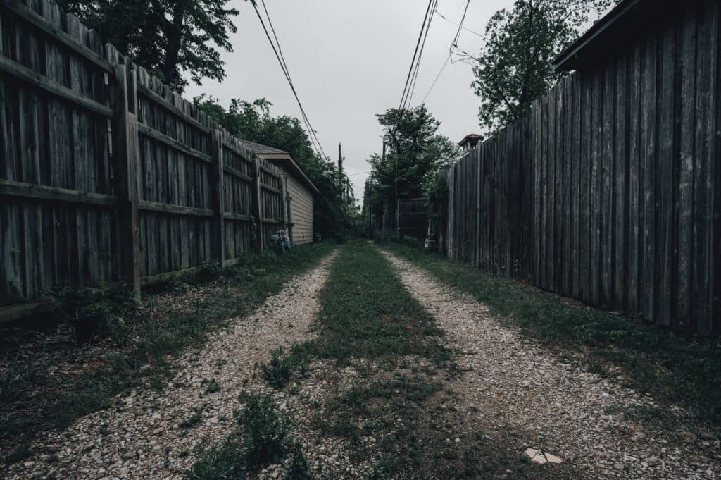 Two neighboring properties' wood privacy fences facing each other along a shared side alley