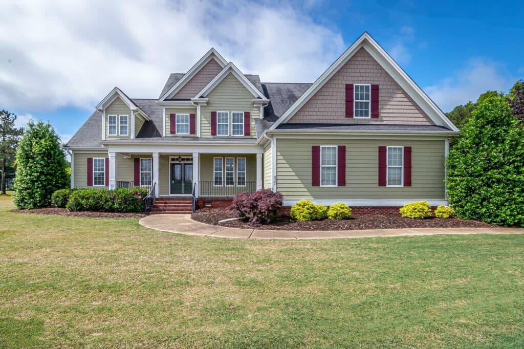 Two-story suburban house with manicured foundation planting beds and a curved front walkway